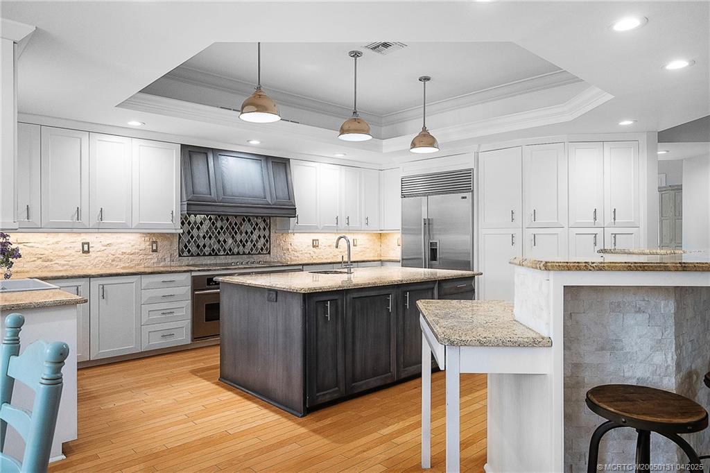6655 Southwest Gaines Avenue Stuart, FL 34997 - Photo 18 of 48 a kitchen with stainless steel appliances granite countertop a sink a stove a refrigerator cabinets and chairs