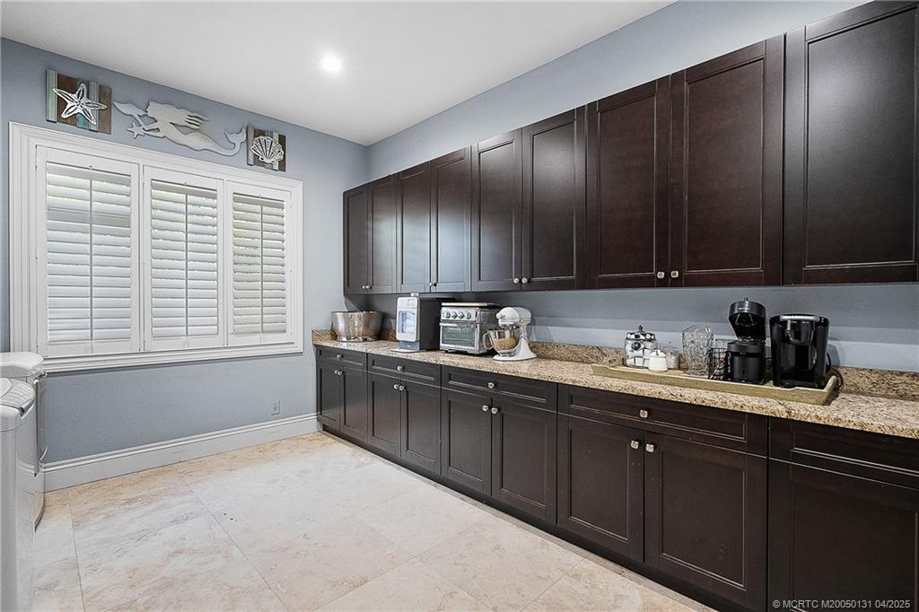 6655 Southwest Gaines Avenue Stuart, FL 34997 - Photo 28 of 48 a kitchen with granite countertop wooden cabinets a sink and dishwasher next to a window