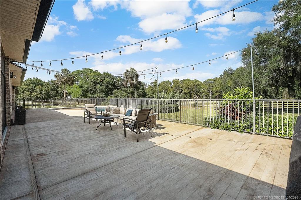 6655 Southwest Gaines Avenue Stuart, FL 34997 - Photo 37 of 48 a roof deck with table and chairs a barbeque with wooden floor and fence