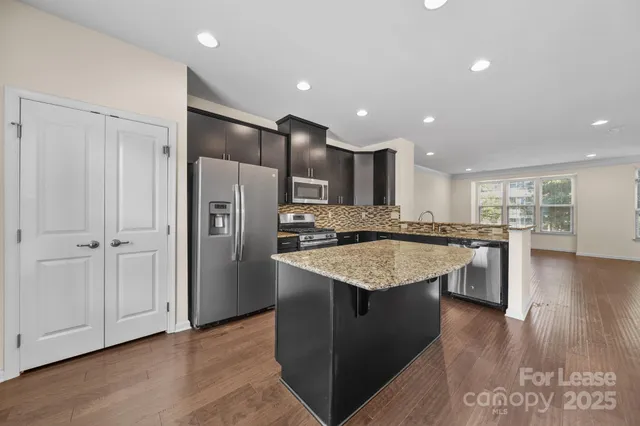 a kitchen with stainless steel appliances granite countertop a refrigerator a sink and a stove
