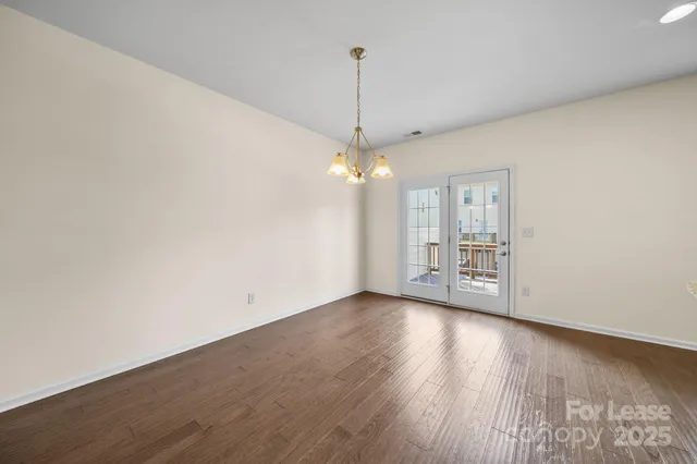 a view of a room with wooden floor chandelier and a window