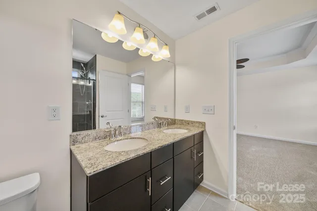 a bathroom with a granite countertop sink a toilet and a mirror