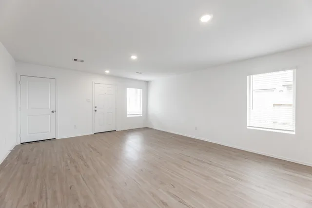 an empty room with wooden floor and window