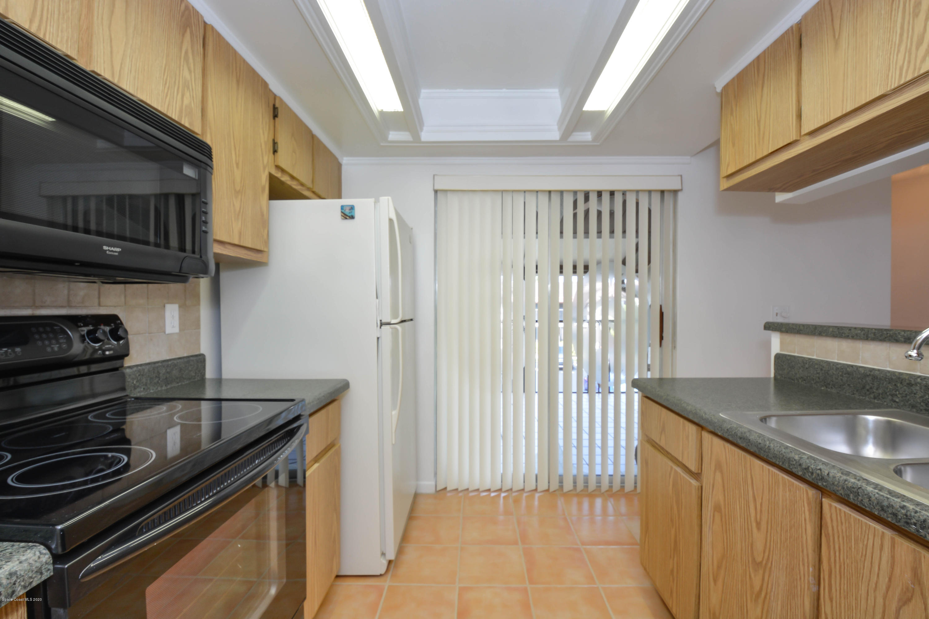 610 North Wickham Road, Unit 74 Melbourne, FL 32935 - Photo 11 of 46 a kitchen with granite countertop a sink stove and refrigerator