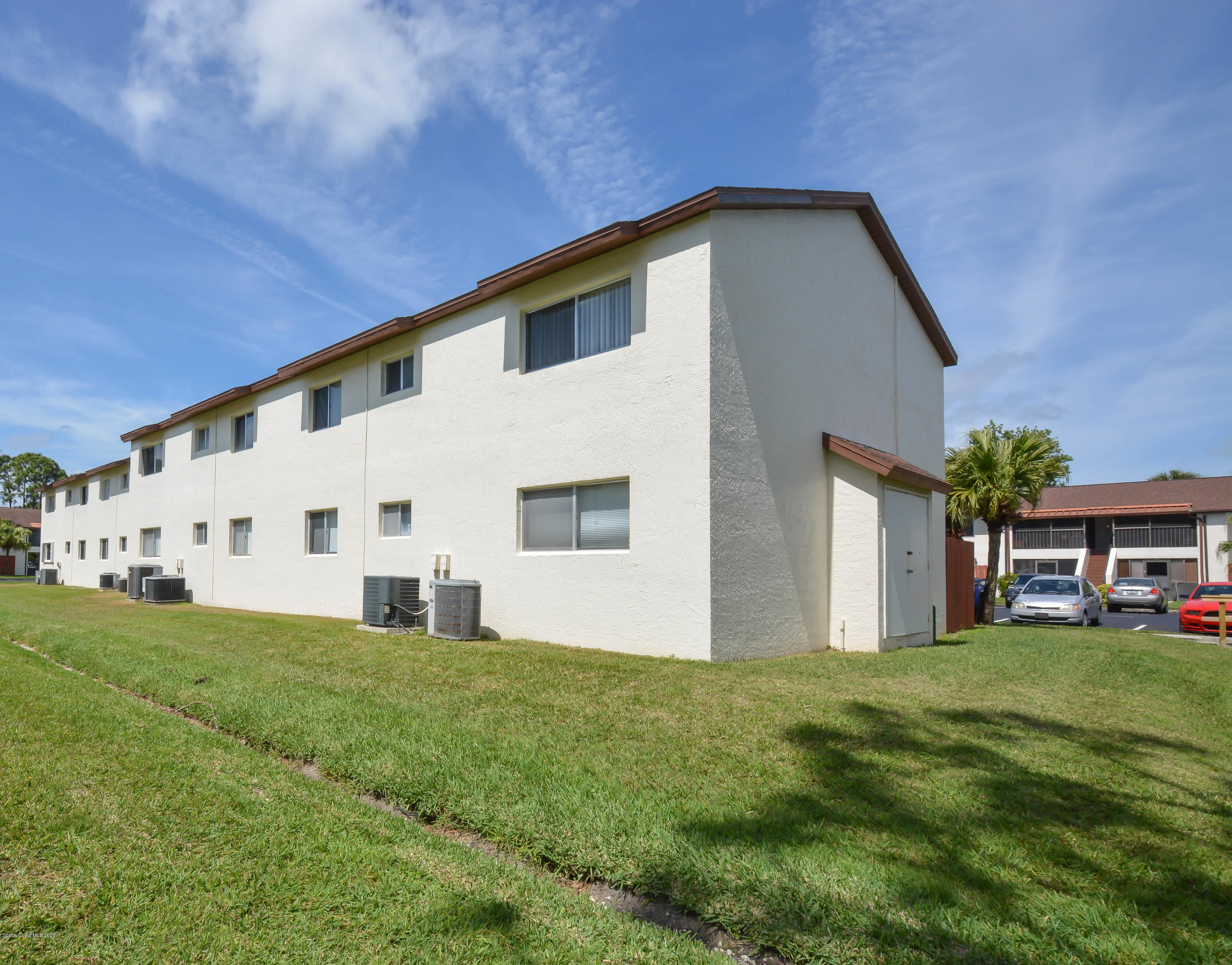 610 North Wickham Road, Unit 74 Melbourne, FL 32935 - Photo 22 of 46 a large white house with a big yard and large trees
