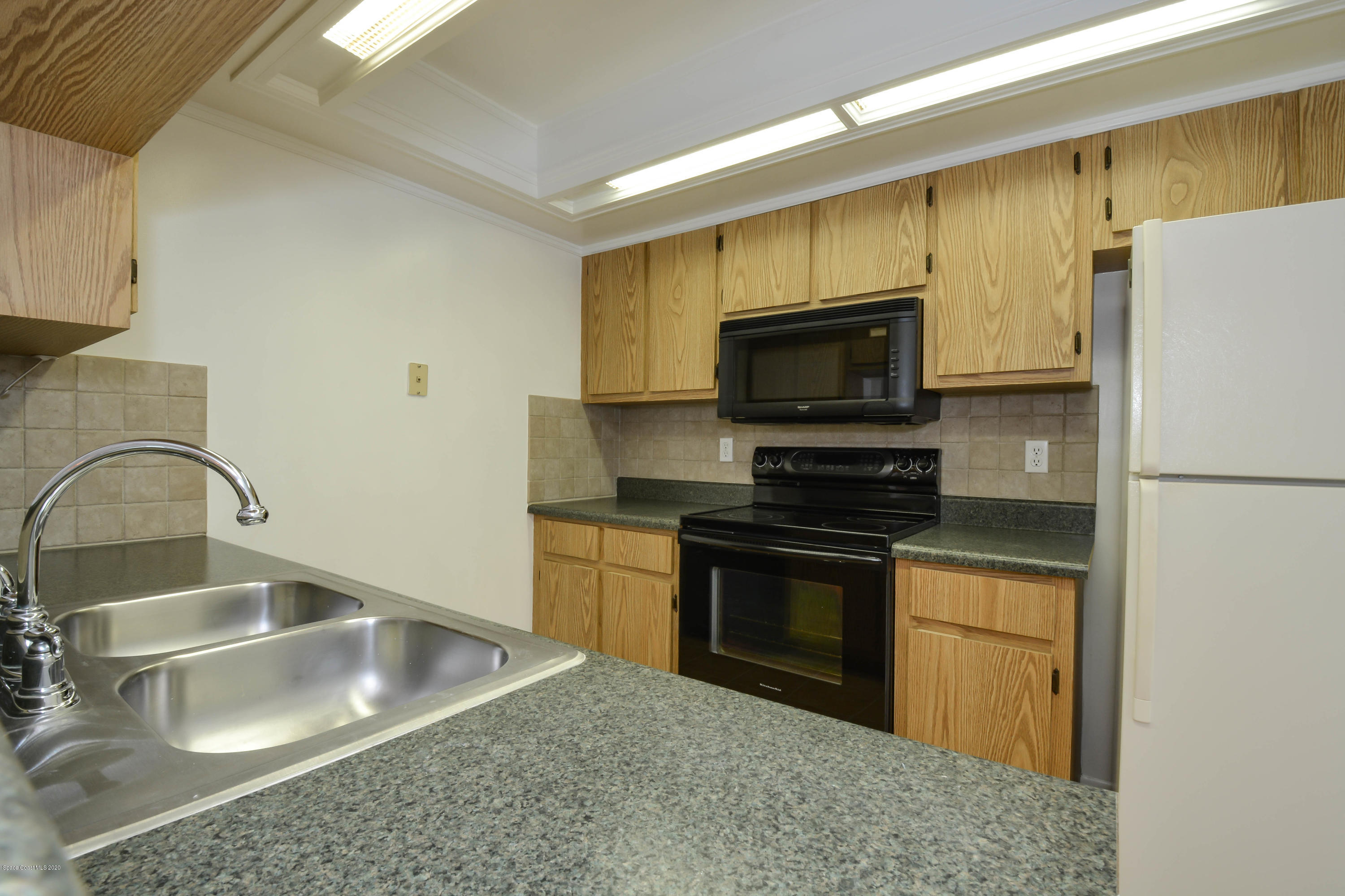 610 North Wickham Road, Unit 74 Melbourne, FL 32935 - Photo 34 of 46 a kitchen with stainless steel appliances granite countertop a sink stove and refrigerator