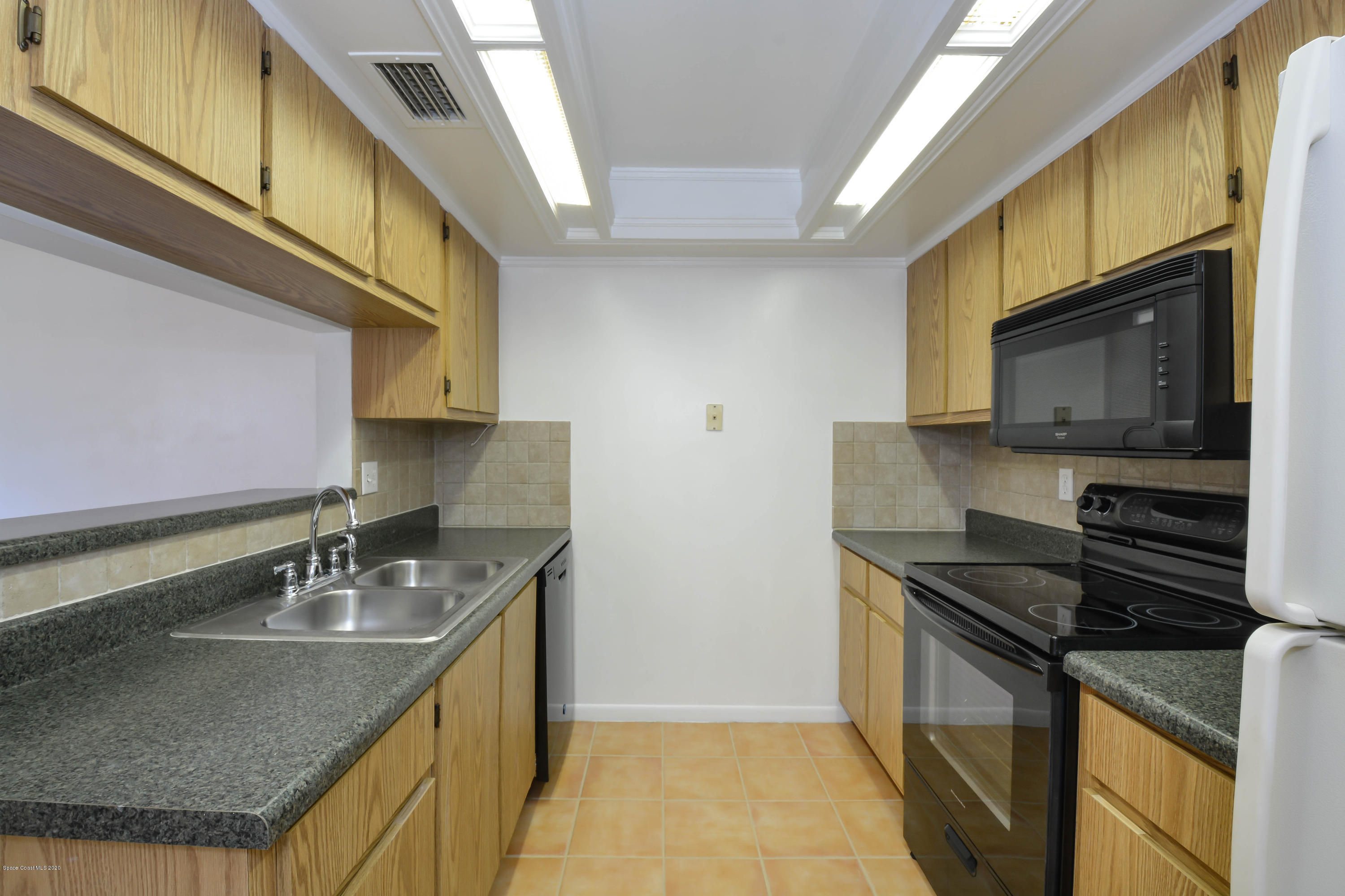 610 North Wickham Road, Unit 74 Melbourne, FL 32935 - Photo 35 of 46 a kitchen with stainless steel appliances granite countertop a sink a stove and a microwave
