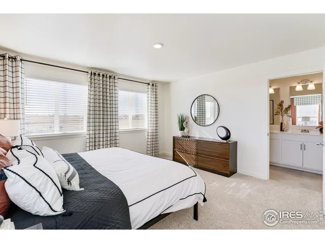 a bedroom with a bed a mirror on dresser and a window