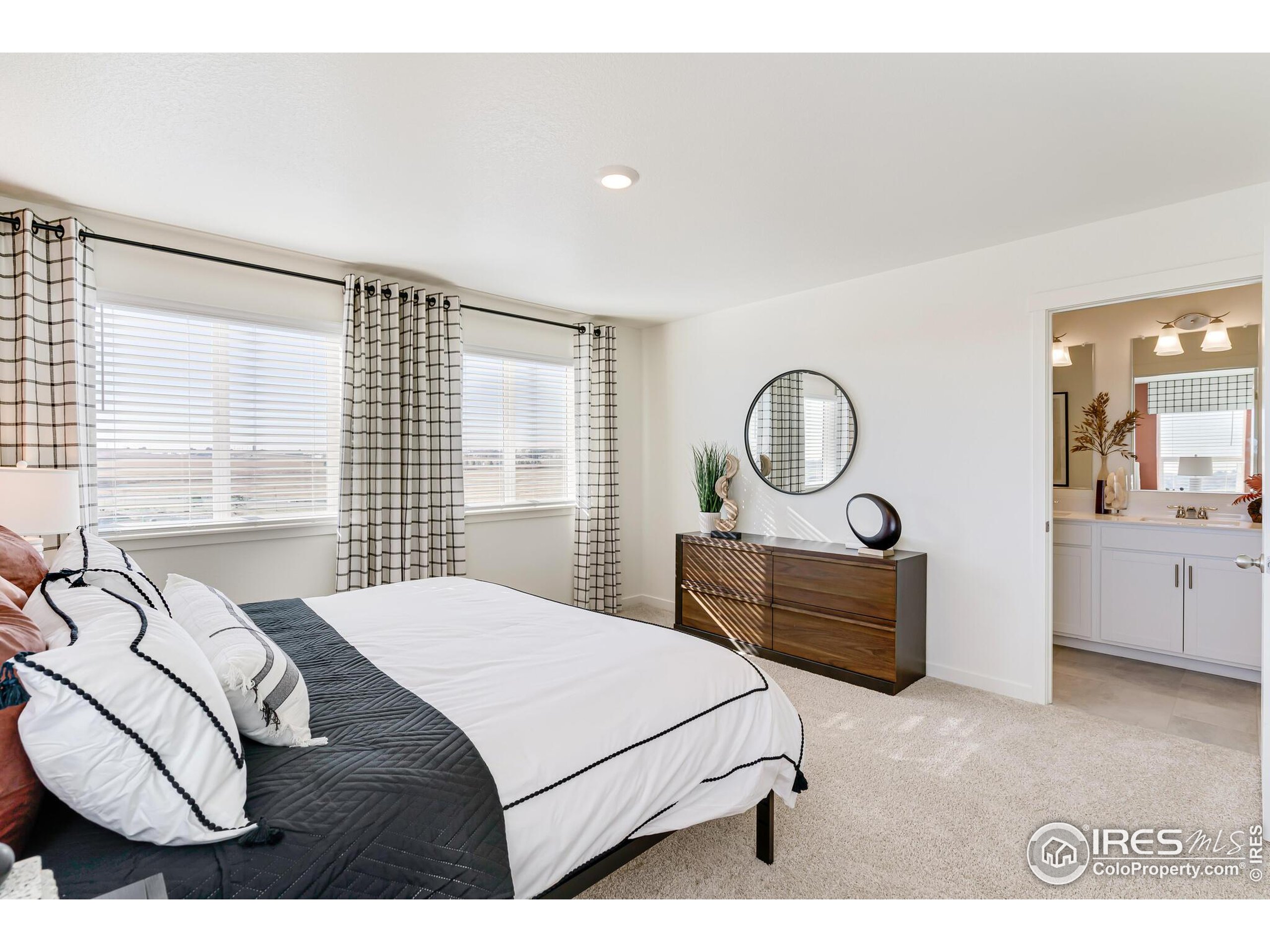 920 Logan Peak Way Berthoud, CO 80513 - Photo 20 of 35 a bedroom with a bed a mirror on dresser and a window