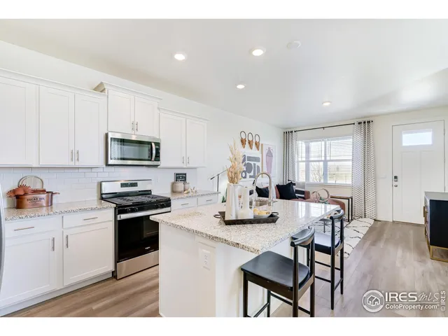 a kitchen with stainless steel appliances kitchen island granite countertop a stove a sink a dining table and chairs