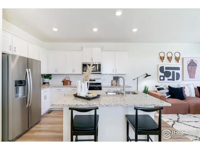 a kitchen with stainless steel appliances kitchen island granite countertop a refrigerator a stove a sink and chairs