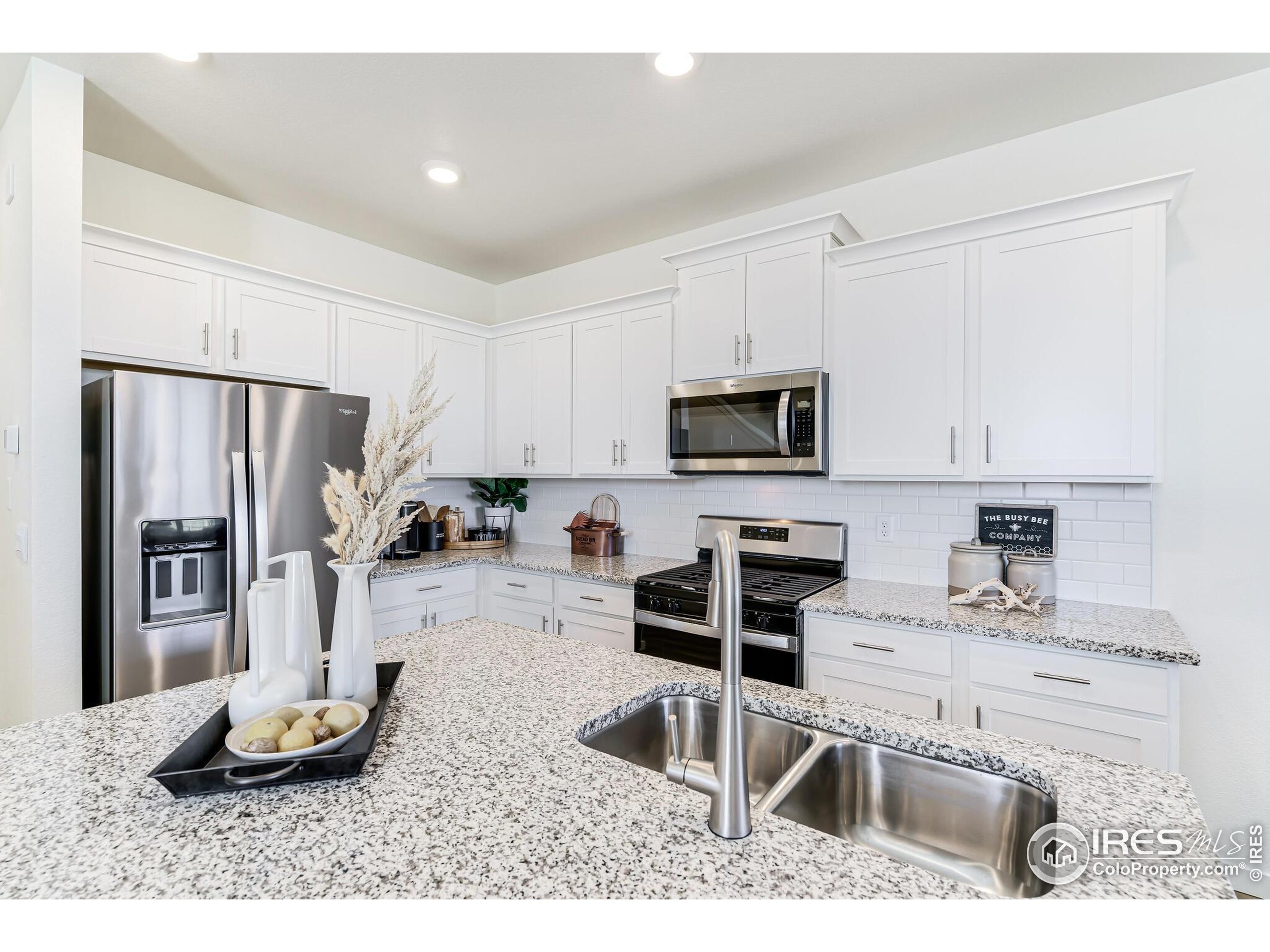 920 Logan Peak Way Berthoud, CO 80513 - Photo 9 of 35 a kitchen with stainless steel appliances kitchen island granite countertop a sink refrigerator and microwave