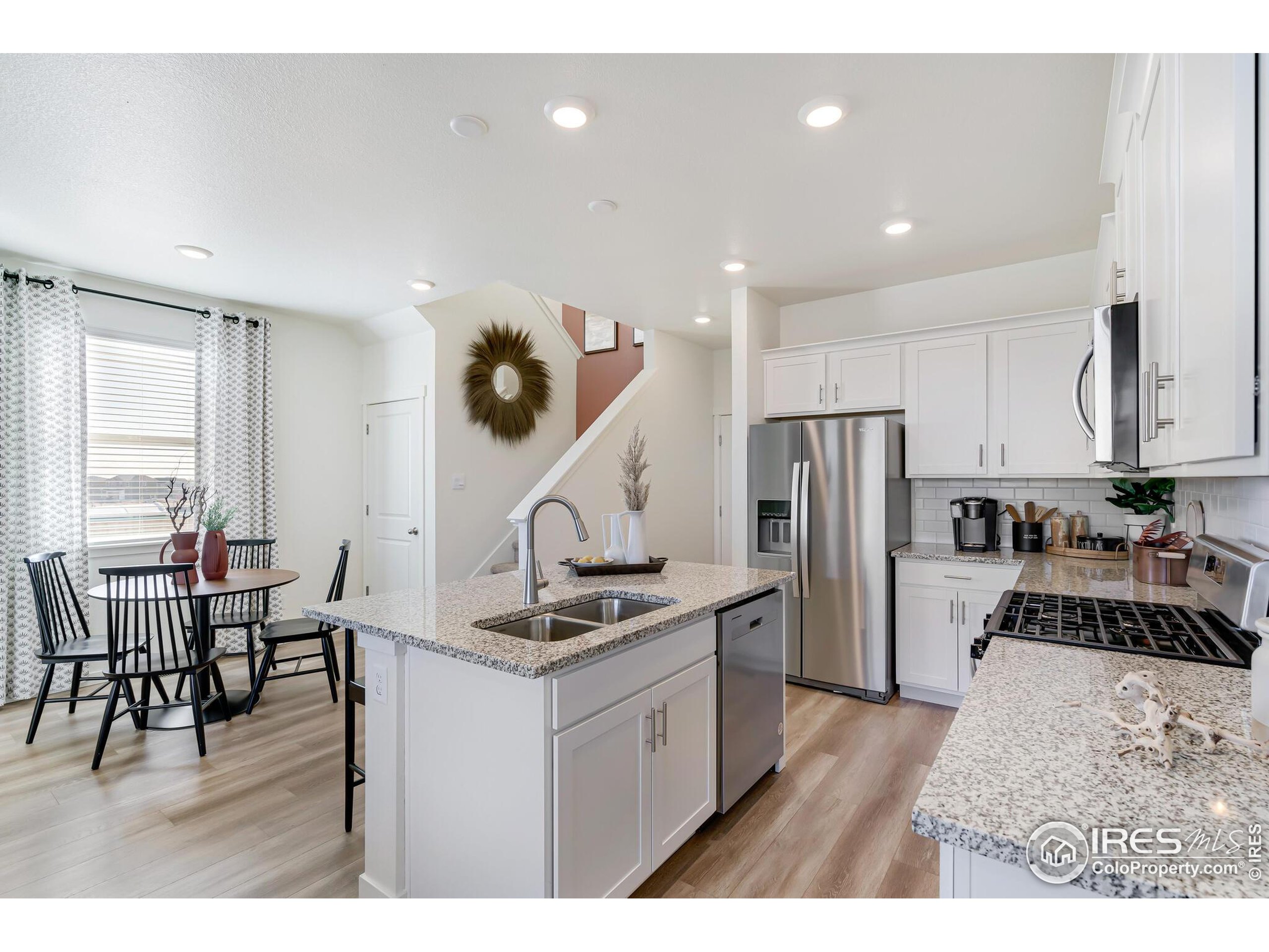 920 Logan Peak Way Berthoud, CO 80513 - Photo 10 of 35 a kitchen with a table chairs and a view of living room