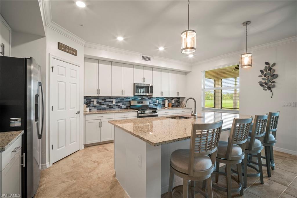 15919 Grassland Lane, Unit 4211 Babcock Ranch, FL 33982 - Photo 10 of 35 a kitchen with stainless steel appliances granite countertop a refrigerator a sink dishwasher a dining table and chairs with wooden floor