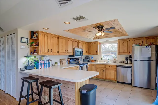 a kitchen with stainless steel appliances granite countertop a stove a refrigerator a sink a dining table and chairs with wooden floor