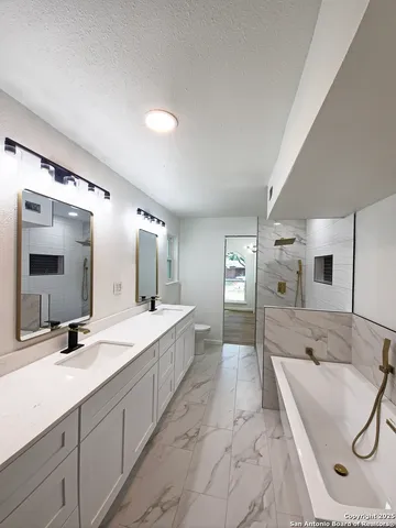 a spacious bathroom with a double vanity sink mirror and bathtub