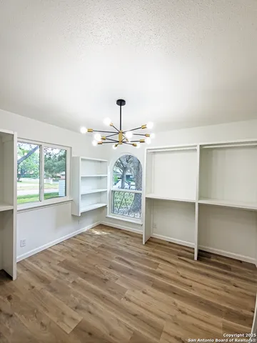 an empty room with wooden floor closet and windows