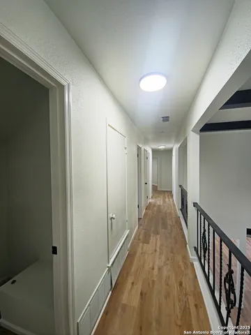a view of a hallway with wooden floor and stairs