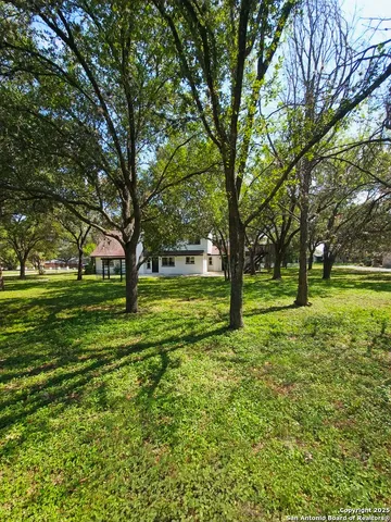 a view of grassy field with benches and trees