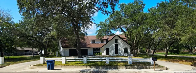 a front view of a building with trees and plants