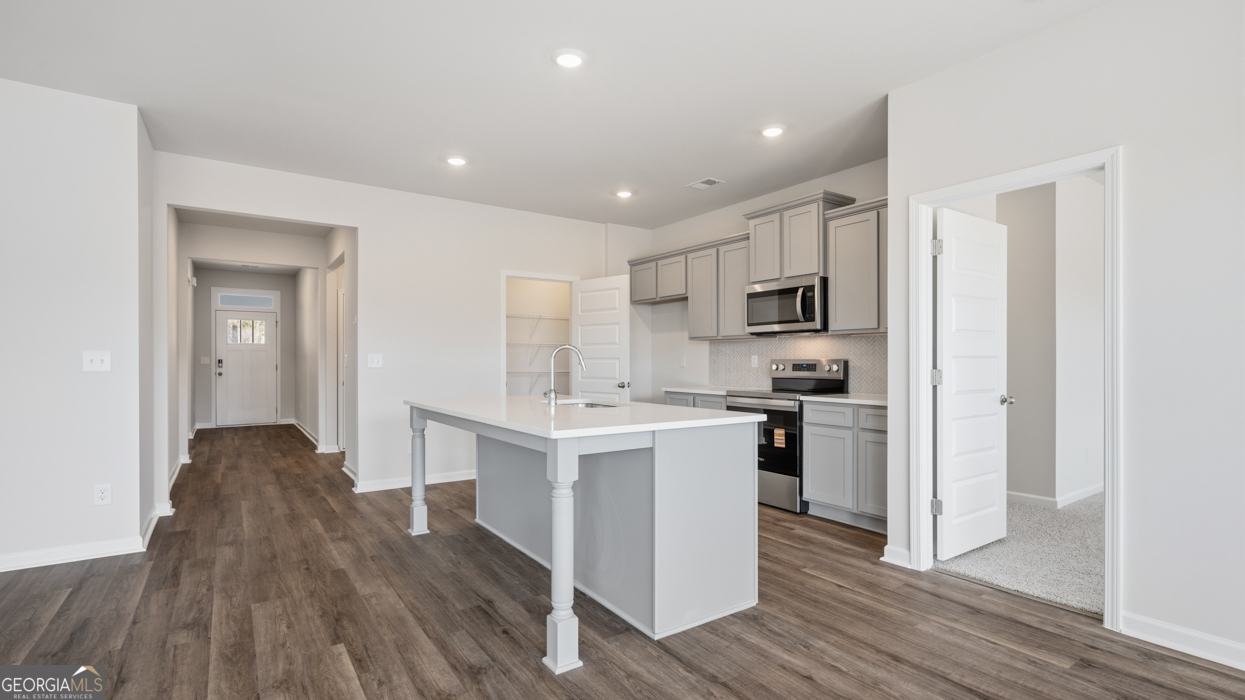 8583 Preakness Pass Snellville, GA 30039 - Photo 13 of 30 a kitchen with white cabinets and stainless steel appliances