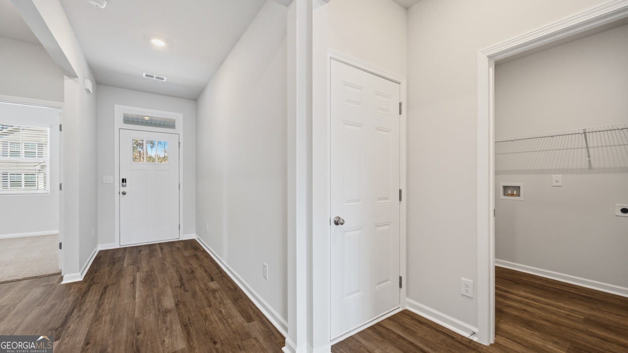 8583 Preakness Pass Snellville, GA 30039 - Photo 7 of 30 a view of a hallway with wooden floor and staircase