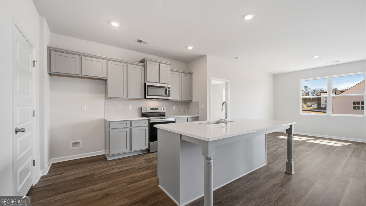 8583 Preakness Pass Snellville, GA 30039 - Photo 9 of 30 a kitchen with white cabinets appliances and wooden floor