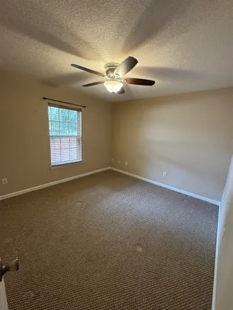 an empty room with windows and fan