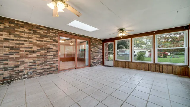 an empty room with windows and ceiling fan