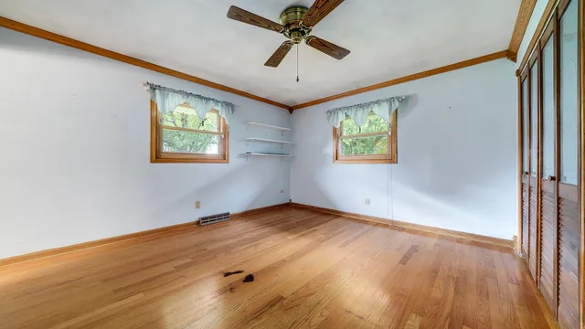 an empty room with wooden floor and windows