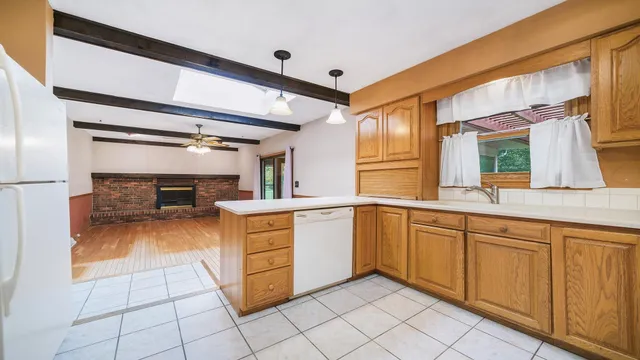 a large kitchen with white cabinets a sink dishwasher and a stove with wooden floor