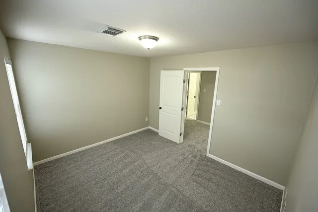 an empty room with windows and chandelier fan