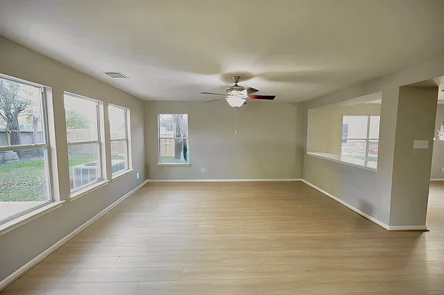 a view of an empty room with window and wooden floor