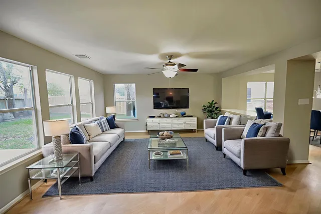an empty room with wooden floor fan and windows