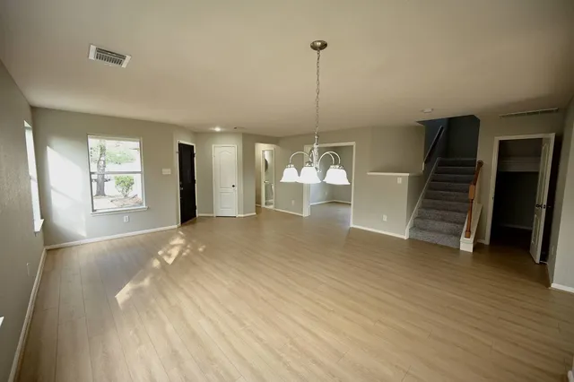 a view of empty room with wooden floor and stairs