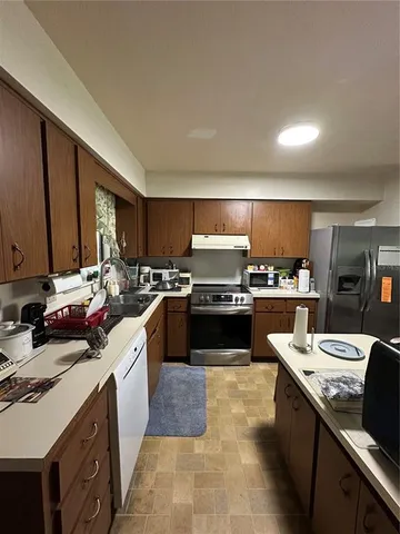 a kitchen with stainless steel appliances a sink a stove top oven a counter space and cabinets