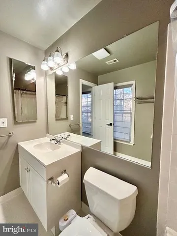 a view of an empty room with wooden floor and a ceiling fan