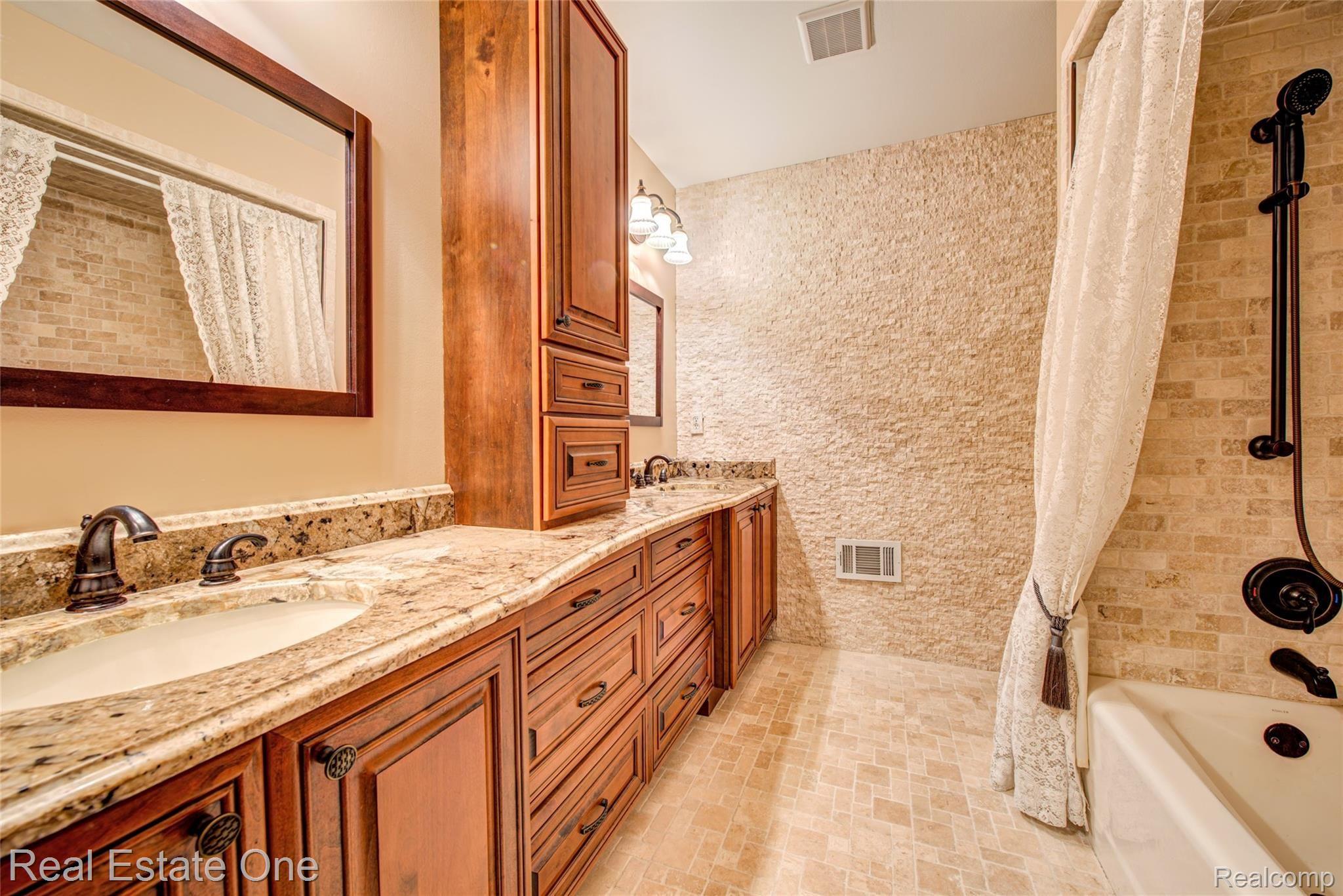 3274 Quail Ridge Circle Rochester, MI 48309 - Photo 46 of 74 Main upstairs bathroom with double vanity, granite counters, stone wall