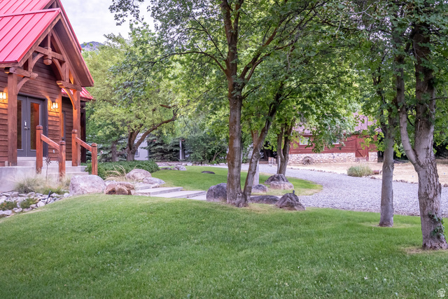 435 Canyon Road Millville, UT 84326 - Photo 5 of 113 Exterior featuring a prominent red metal roof, timber-frame porch entry, and wood-paneled siding
