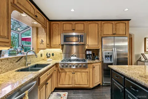 a kitchen with kitchen island granite countertop wooden cabinets a sink and stainless steel appliances