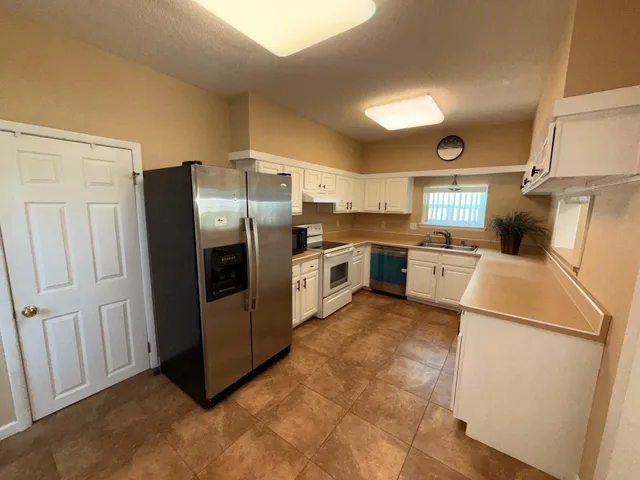 a kitchen with granite countertop a refrigerator a sink a stove and cabinets