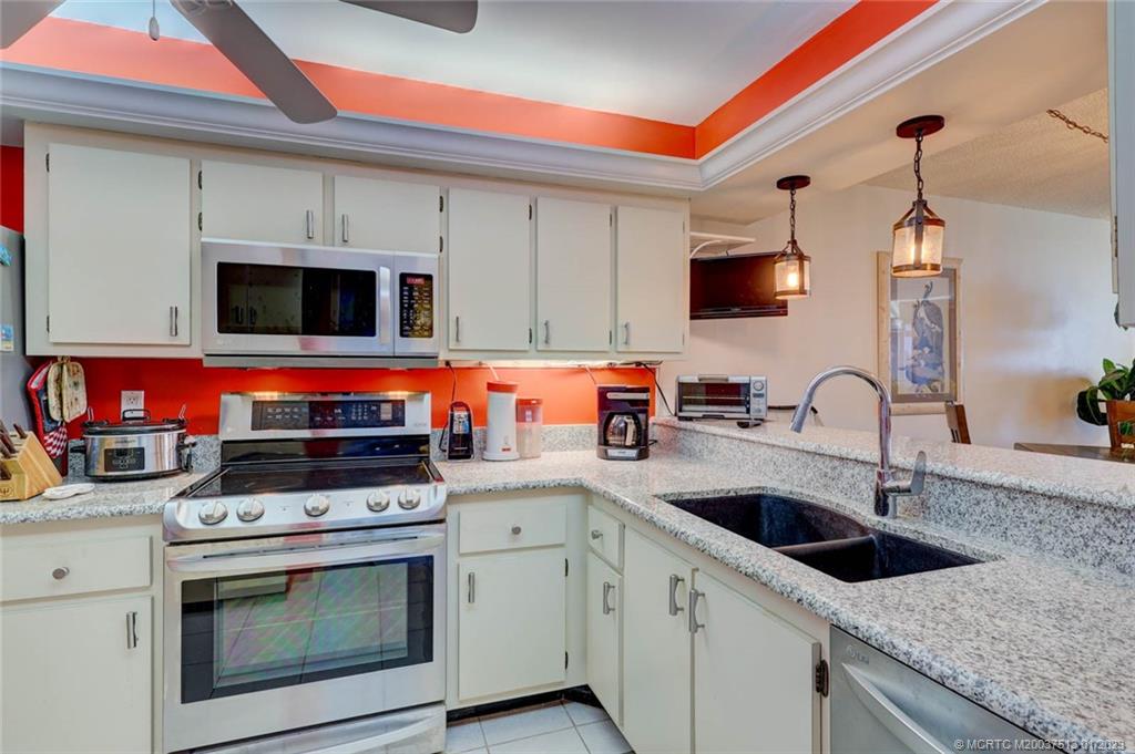 1950 Southwest Palm City Road, Unit 5306 Stuart, FL 34994 - Photo 18 of 55 a kitchen with stainless steel appliances granite countertop a stove a sink and a microwave