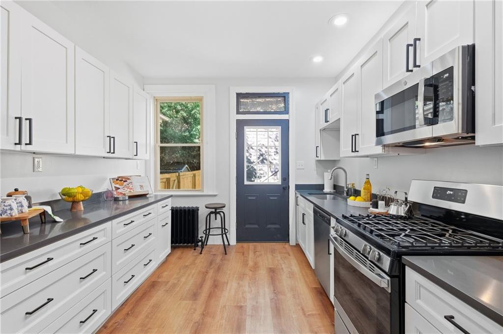 848 Grand Avenue Pittsburgh, PA 15212 - Photo 13 of 33 a kitchen with stainless steel appliances granite countertop a stove a sink dishwasher and cabinets with wooden floor