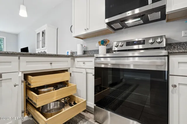 a kitchen with a dining table chairs wooden floor cabinets and appliances