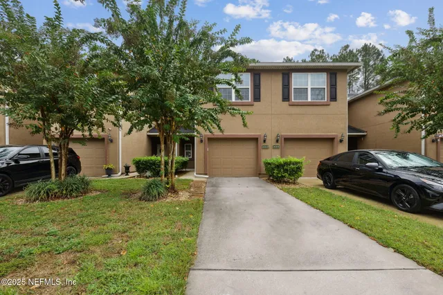 a front view of a house with a garden and tree