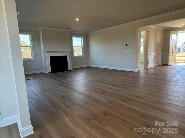 an empty room with wooden floor fireplace and windows