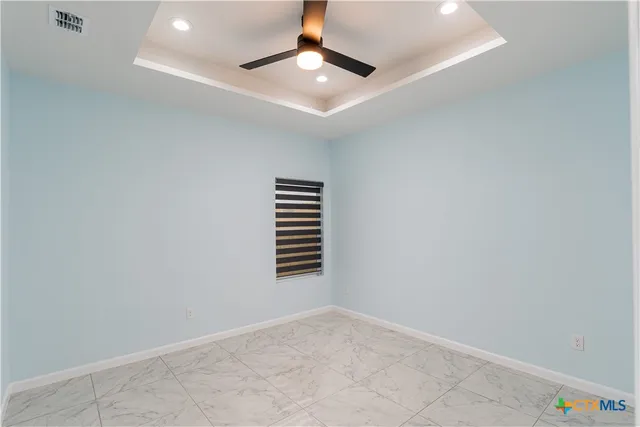 an empty room with a ceiling fan and window