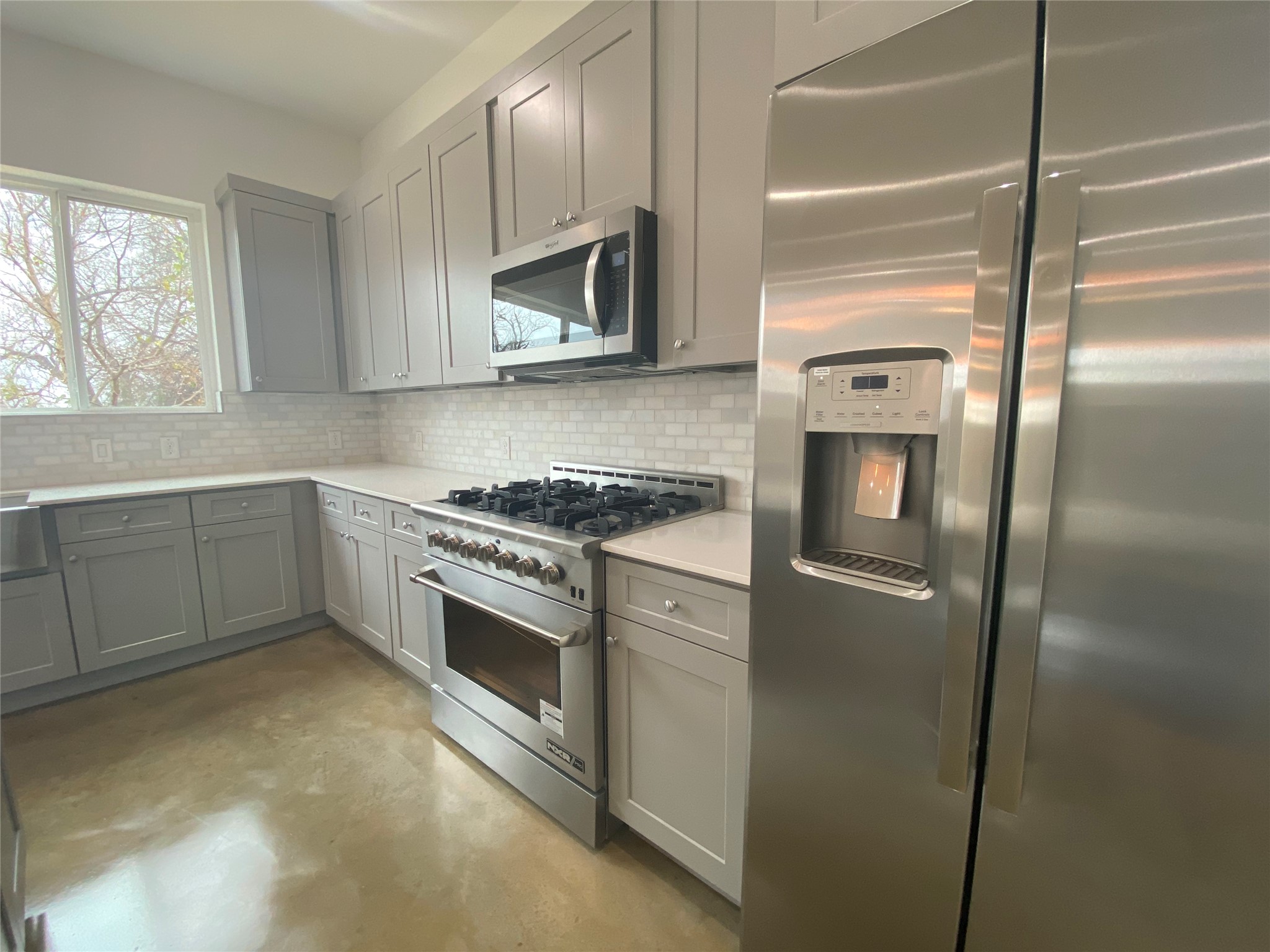 1916 Webberville Road, Unit B Austin, TX 78721 - Photo 7 of 25 Contemporary kitchen featuring light gray cabinetry, stainless steel appliances, white subway tile backsplash, and light-colored countertops