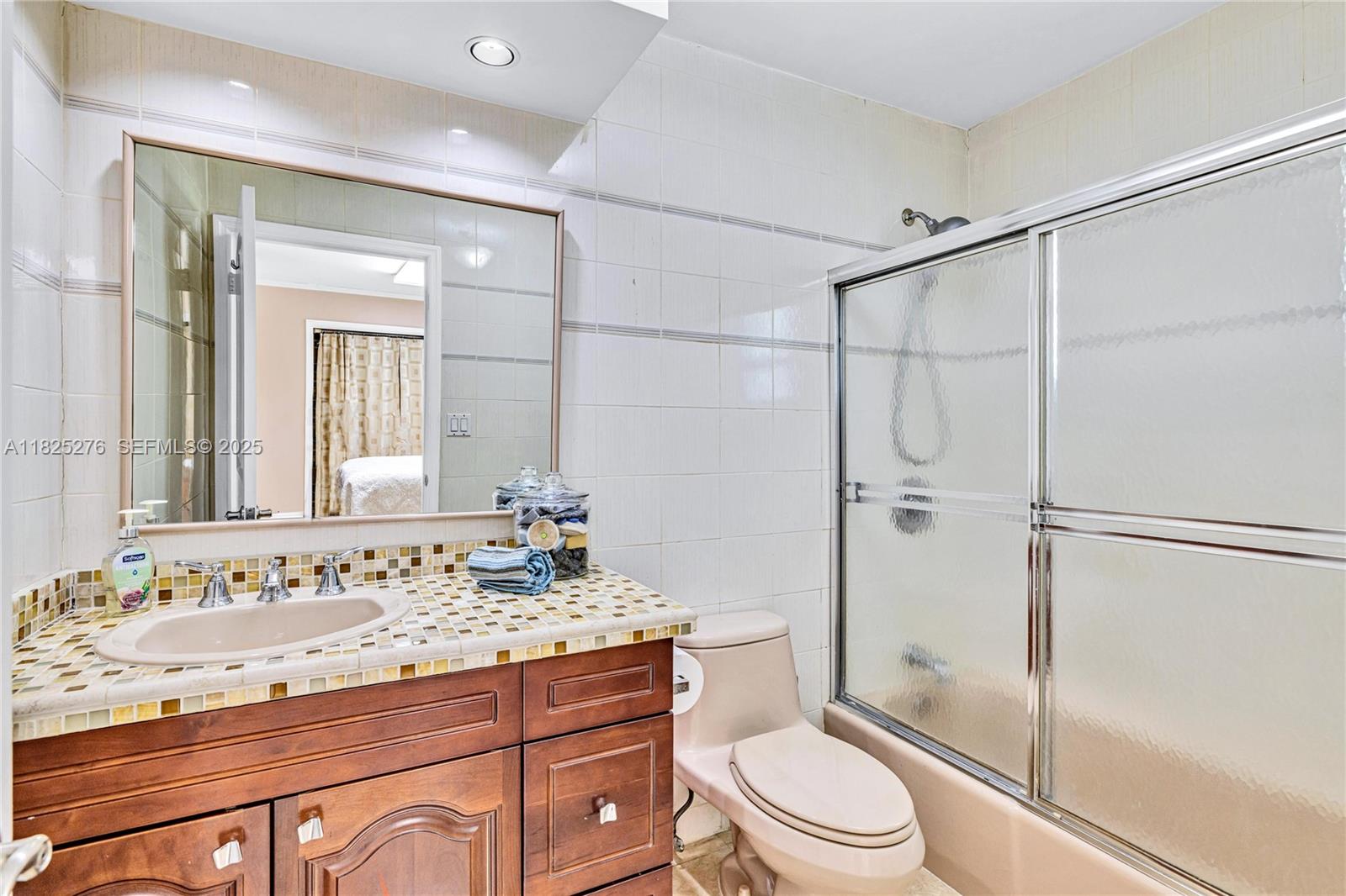 10563 Southwest 92nd Avenue Miami, FL 33176 - Photo 49 of 87 a bathroom with a granite countertop sink toilet a mirror a vanity and shower