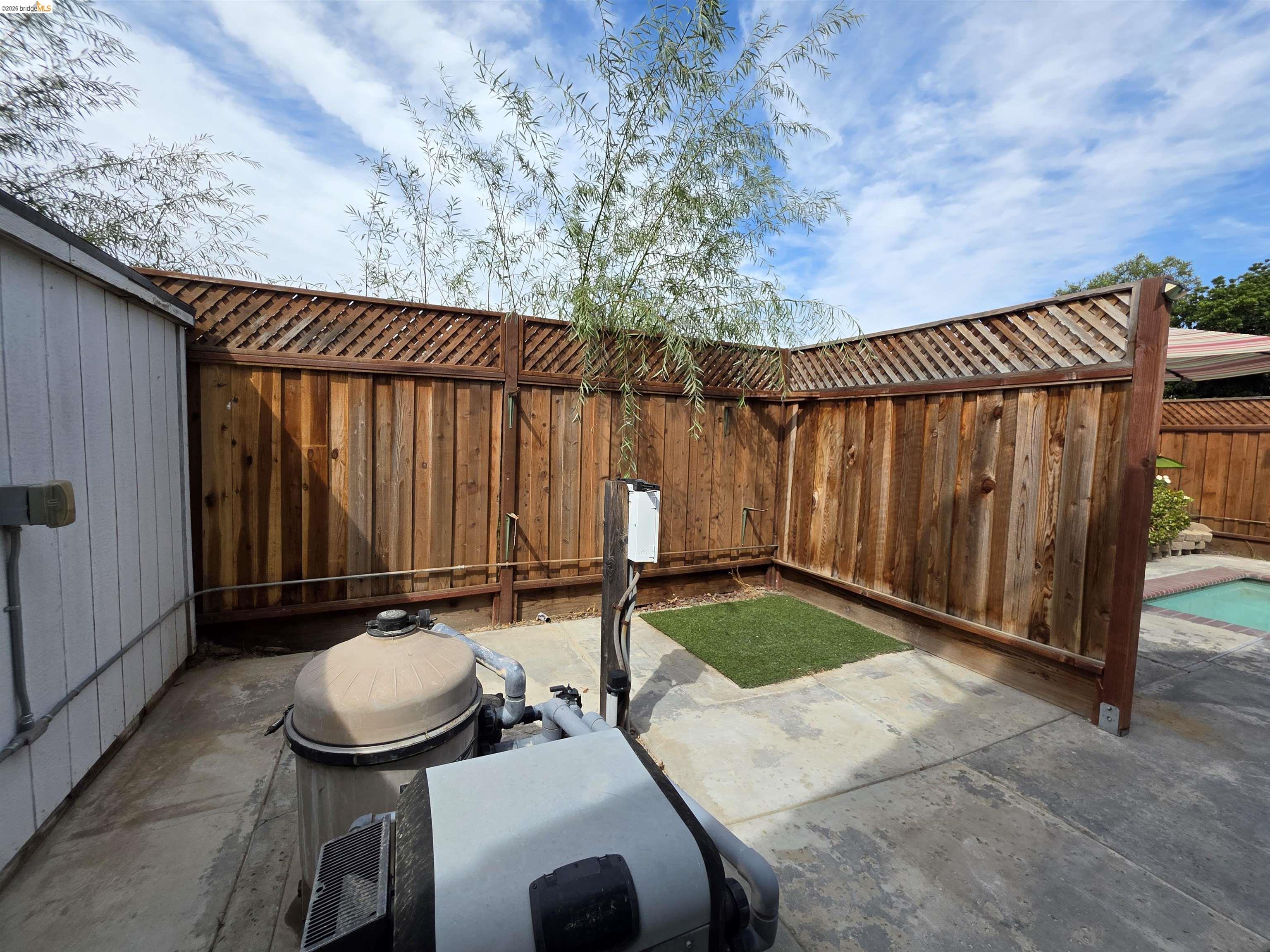 2607 Glow Road Riverbank, CA 95367 - Photo 41 of 42 Wood-paneled fencing with lattice top, concrete patio area, and partial pool visible